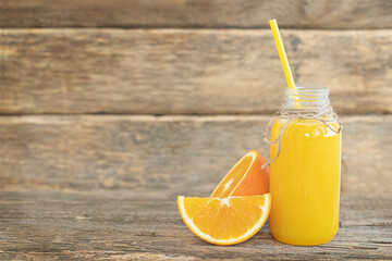 The bottle of orange juice and sliced orange on the wooden background	