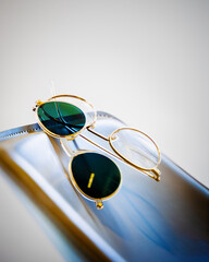 get&ouml;nte Sonnenbrille zum aufstecken an goldenes Brillengestell auf blauen Leder