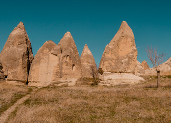 Fototapeta na wymiar Beautiful panorama view of a field and caves inside typical rock formations and fairy chimneys in Cappadocia, Turkey