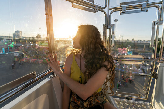 Una mujer joven pasando el tiempo en una noria en el parque de atracciones