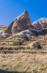 Beautiful panorama view of a field and caves inside typical rock formations and fairy chimneys in Cappadocia, Turkey