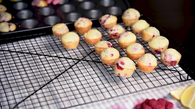 Woman's Hand Removing Mini Raspberry Lemon Muffins From Muffin Tin And Placing On Cooling Rack. Baking.