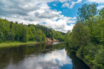 Fototapeta na wymiar Landscape view of red sandstone caves on Gauja river in Sigulda, Latvia on a cloudy spring day