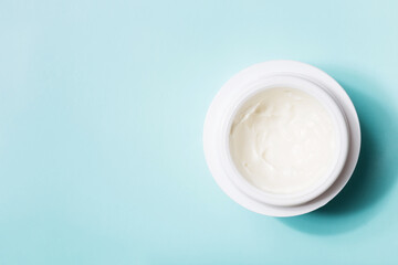 jar of white cream on blue background with copy space. concept of cosmetics, skin care.