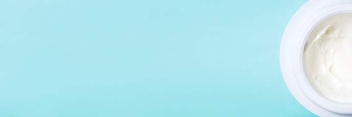 jar of white cream on blue background with copy space. concept of cosmetics, skin care.