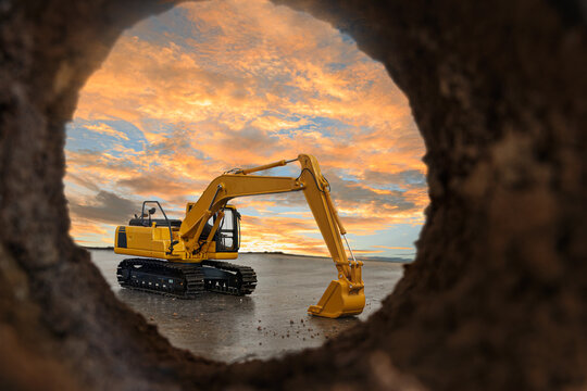 Crawler excavator are digging soil in the tunnel construction site. With a sky after sunset background