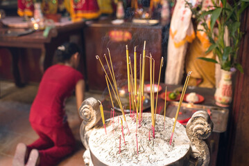 Burning incense sticks and blurred woman praying at Ha Chuong Hoi Quan Pagoda in Cho Lon District, Saigon, Vietnam　ホーチミン・チョロンの寺院 線香と祈る女性 霞彰會館（媽祖天后廟）