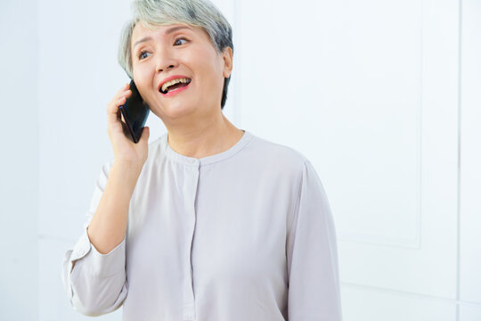 Senior Asia woman is talking on her mobile phone. Senior woman has a happy conversation at cellphone.