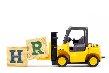 Toy forklift hold letter block R to complete word HR (Abbreviation of human resource) on wood background