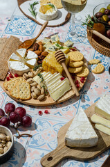 Cheese plate with variety of appetizers on table. Fresh brie cheese and camembert cheese whith crackers, pears, grapes, olives, rosemary, orange jam, orange jam, nuts, honeycomb and wine.