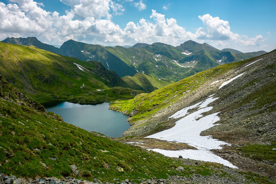 mountain summer landscape with alpine lake. beautiful nature scenery of fagaras mountain ridge, romania. sunny weather with fluffy clouds on the sky. popular travel destination