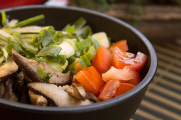 A closeup photo of poke with tomato, slices of shiitake and chives. 