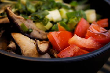 A closeup photo of poke with tomato, slices of shiitake and chives. 