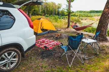 man laying on hammock at lake beach near camp fire