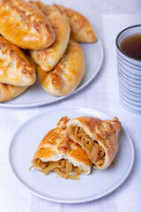Pies (pirozhki) with cabbage. Homemade baking. Traditional Russian and Ukrainian cuisine. In the background is a dish with pies. Close-up.