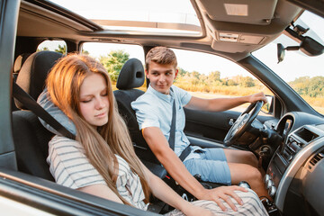 young man driving car. woman sleeping with pillow