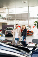 Obraz premium Beautiful couple in car dealership chooses car