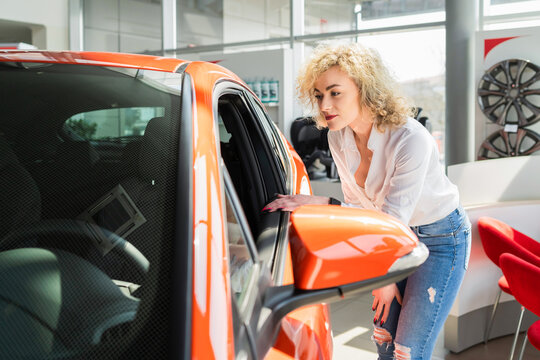 Curly woman looks car at the dealership