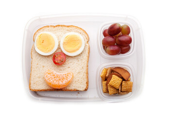School lunch box snacks for kids over white background. Back to school. Healthy and fun snacks options for parents. Food art creative concepts. Bows with fruits and vegetables and cute face sandwich.