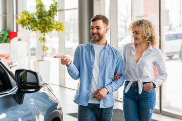 Young couple walks through the car dealership in search of a new car