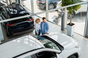 Man and woman in a car dealership top view. Couple choosing their new car