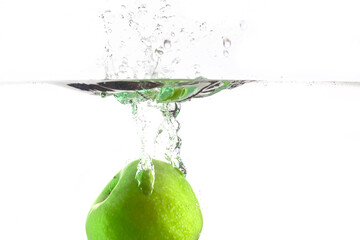 drop one green apple into the water with splashes on a white background
