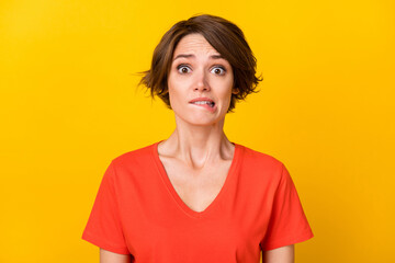 Photo of sad nice brunette lady bite lip wear orange t-shirt isolated on vibrant yellow color background