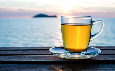 Cup of green tea front of at sunset light on wooden tabletop.