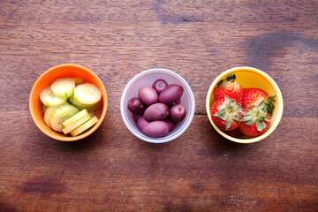 School lunch box snacks for kids over wooden background. Back to school. Healthy and fun snacks options for moms. Cute food art creative concepts. Bows with fruits and vegetables.