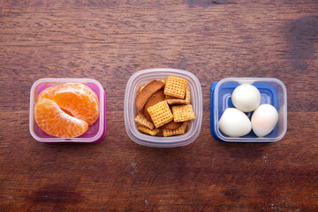 School lunch box snacks for kids over wooden background. Back to school. Healthy and fun snacks options for moms. Cute food art creative concepts. Bows with fruits and vegetables.