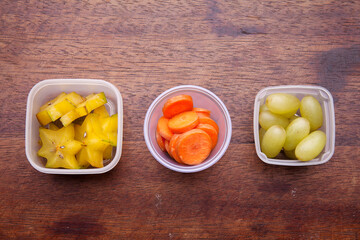 School lunch box snacks for kids over wooden background. Back to school. Healthy and fun snacks options for moms. Cute food art creative concepts. Bows with fruits and vegetables.
