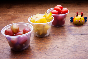 School lunch box snacks for kids over wooden background. Back to school. Healthy and fun snacks options for moms. Cute food art creative concepts. Bows with fruits and vegetables.