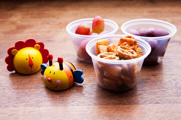 School lunch box snacks for kids over wooden background. Back to school. Healthy and fun snacks options for moms. Cute food art creative concepts. Bows with fruits and vegetables.