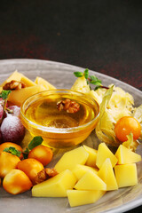 cheese plate with grape, physalis, honey and nuts close up