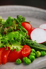 salad with fresh vegetables on plate closeup. salad with tomatoes peas cucumber radishes