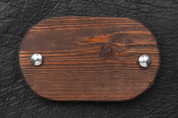 Sign made from a board, fastened with iron rivets on black leather. Top view.