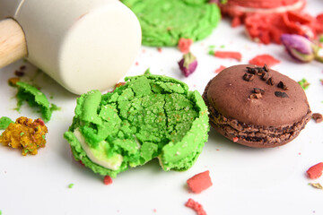 Crushed macaroon of different colors on a white background with a hammer..