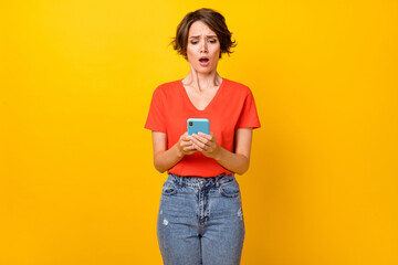 Photo of sad nice brunette lady hold telephone wear orange t-shirt isolated on vibrant yellow color...