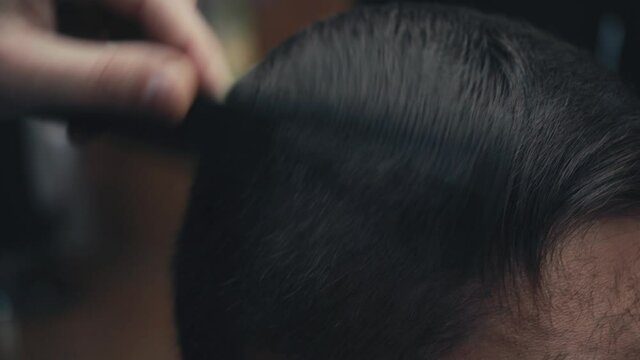 Close up view of barber cutting hair of man