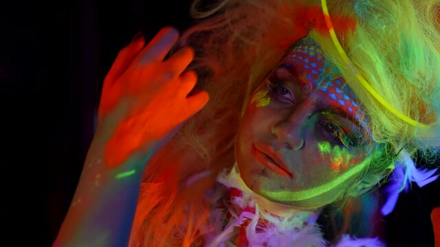 amazing beautiful woman with fluorescent makeup on face and neon hair, closeup portrait