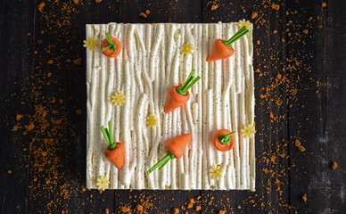 Carrot puff cake with cream and carrot on top on a black background.