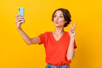Photo of nice brunette optimistic lady do selfie blow kiss show v-sign wear red t-shirt isolated on vivid yellow color background