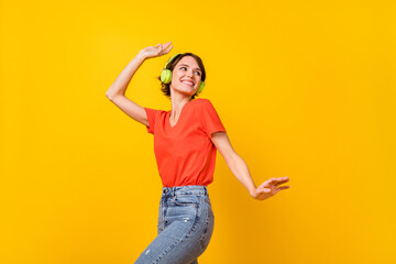 Portrait of cheerful girl look empty space toothy smile listen to favorite single isolated on yellow color background