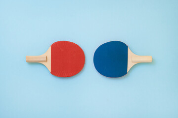 Wooden red and blue pinpong rackets, light blue background