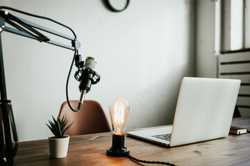 Home studio podcast interior. Microphone, laptop and on air lamp on the table