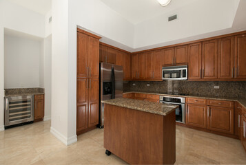 Vacant Kitchen with cherry wood cabinets and center island with granite.