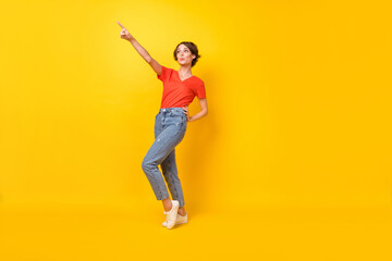 Full size photo of optimistic nice brunette lady point empty space wear orange t-shirt isolated on yellow background
