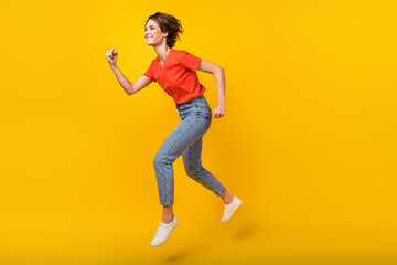Full size profile photo of cool brunette optimistic lady jump wear red t-shirt jeans sneakers isolated on yellow color background