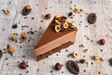 Chocolate cheesecake with hazelnuts on a white wooden background. A slice of cake with coffee..