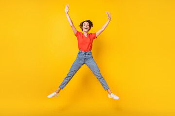 Fototapeta na wymiar Full size photo of cool brunette optimistic lady jump wear red t-shirt jeans sneakers isolated on yellow color background